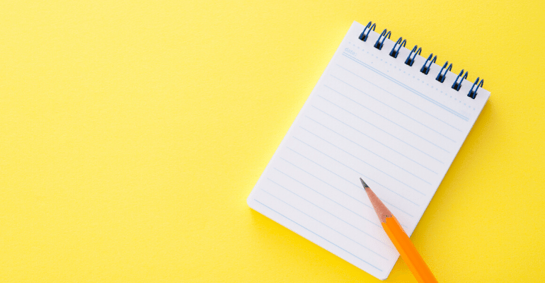 Notepad and pencil against yellow background