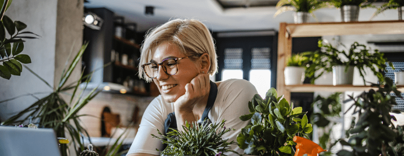 Woman at her computer surrounded by plants. AKA the best work environment.