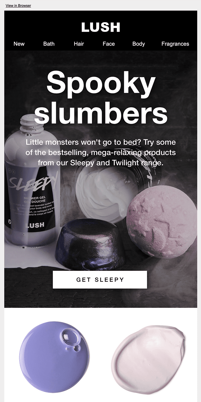 Holiday email example by Lush showing white smoky shampoos and pink bath bombs on a black background. 